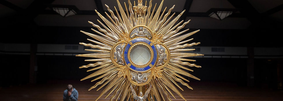 A golden monstrance with the host inside against a dark background